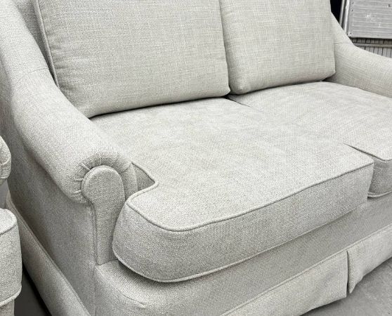 Side view of Reupholstered Loveseat with skirted base and rolled arms in light gray fabric