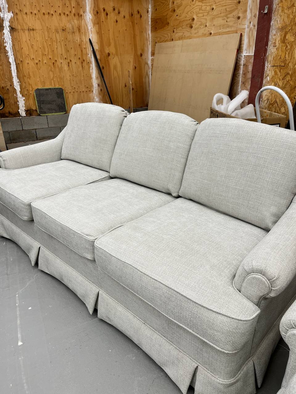 Sideview of Reupholstered Three-cushion Sofa with a Skirted Base in light grey fabric