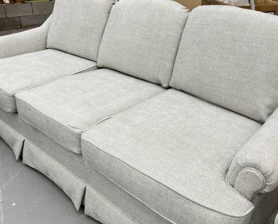 Sideview of Reupholstered Three-cushion Sofa with a Skirted Base in light grey fabric