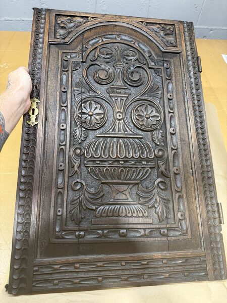 Restored antique carved wooden door with ornate floral scrollwork and urn design