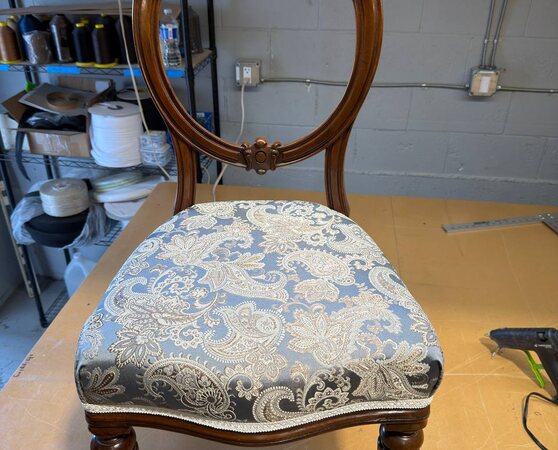 Front view of an ornate round-back chair with a paisley upholstered seat