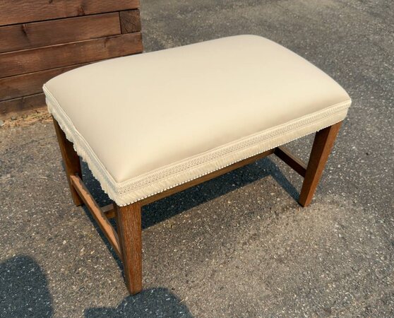 Cream upholstered wooden bench with piping and fringe trim