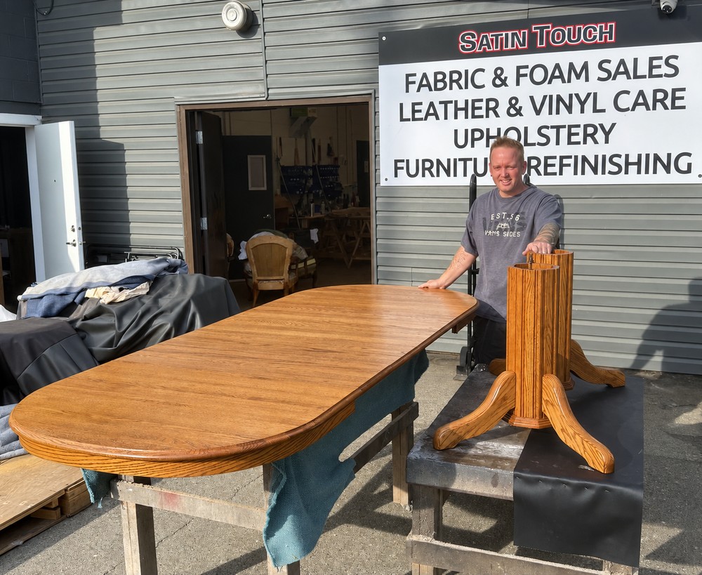 Anthony Vipond beside a golden-finished oak dining tabletop and its double-pedestal base at Satin Touch.