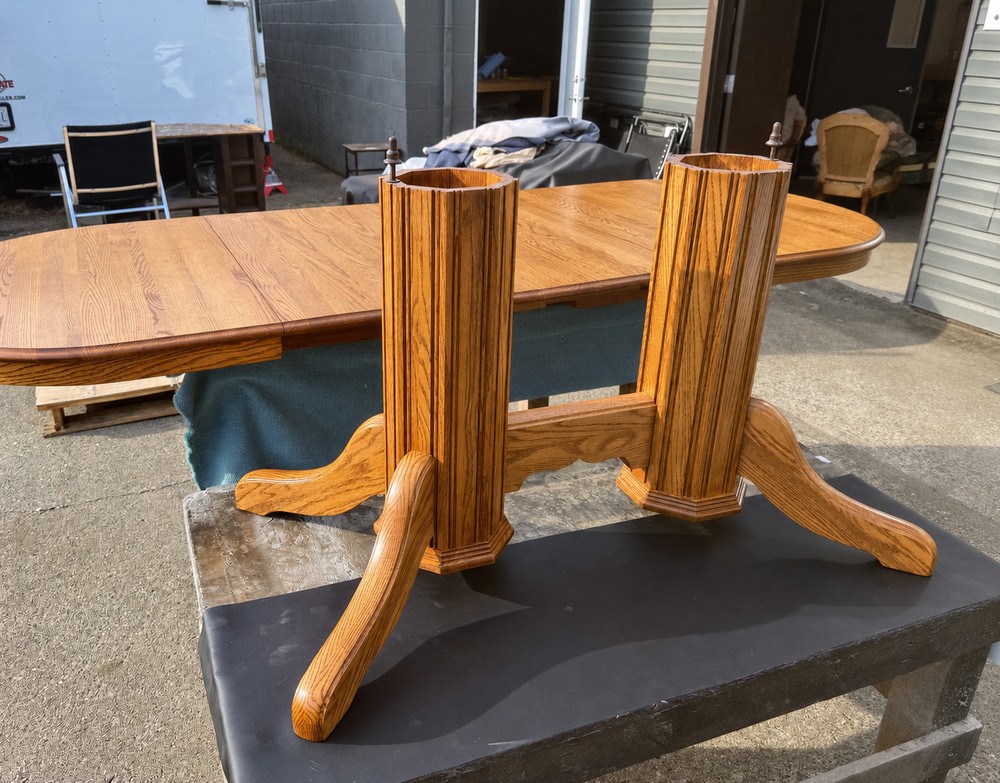 Refinished oak double-pedestal dining table base with curved feet and prominent golden wood grain.